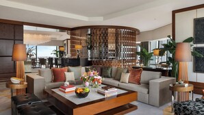 A modern living room with a large sectional sofa, a coffee table with books and fruit, and a decorative wall panel. - Mandarin Oriental, Macau (Macau)