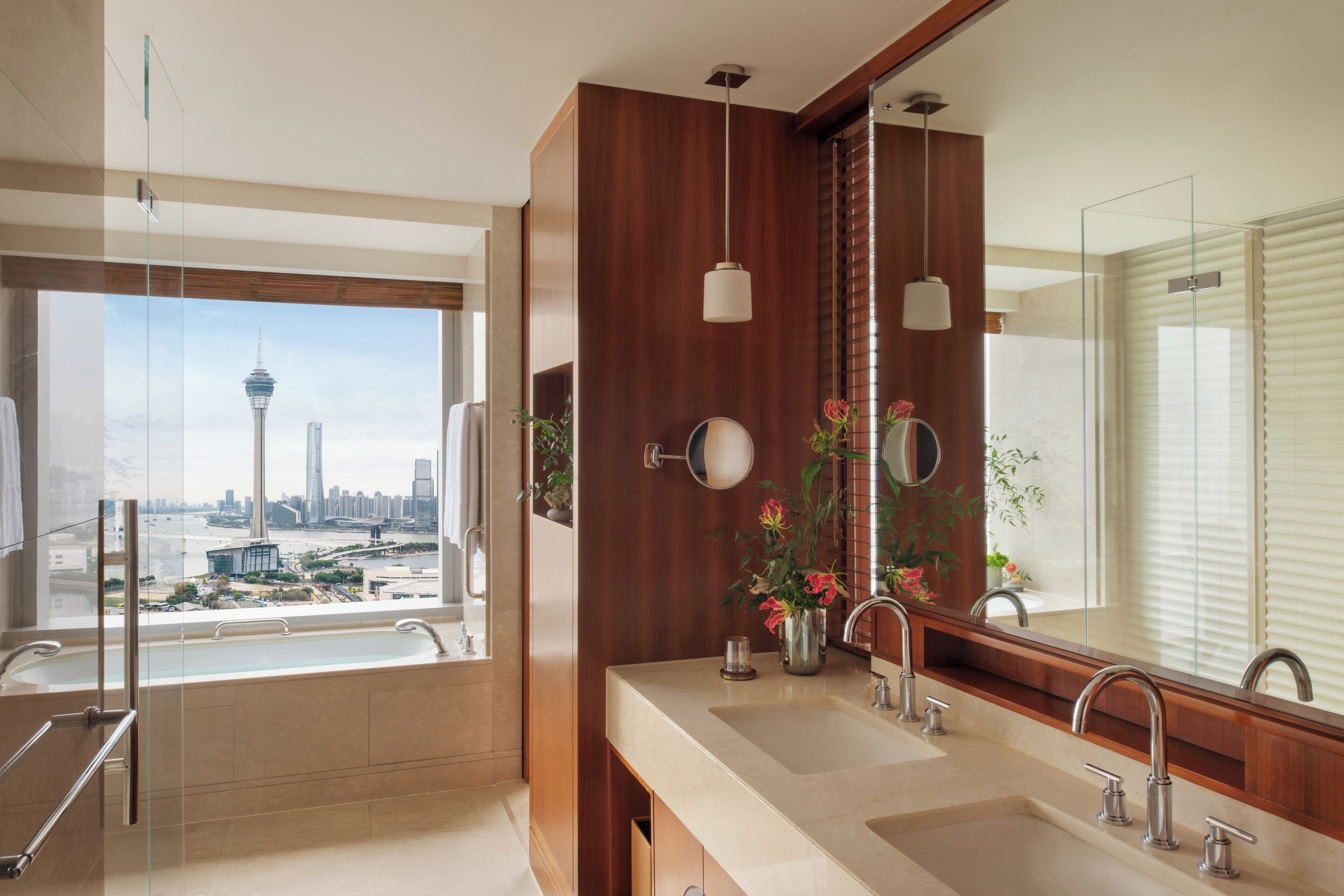 Un baño moderno con un ventanal grande, una bañera, dos lavamanos y un espejo amplio.