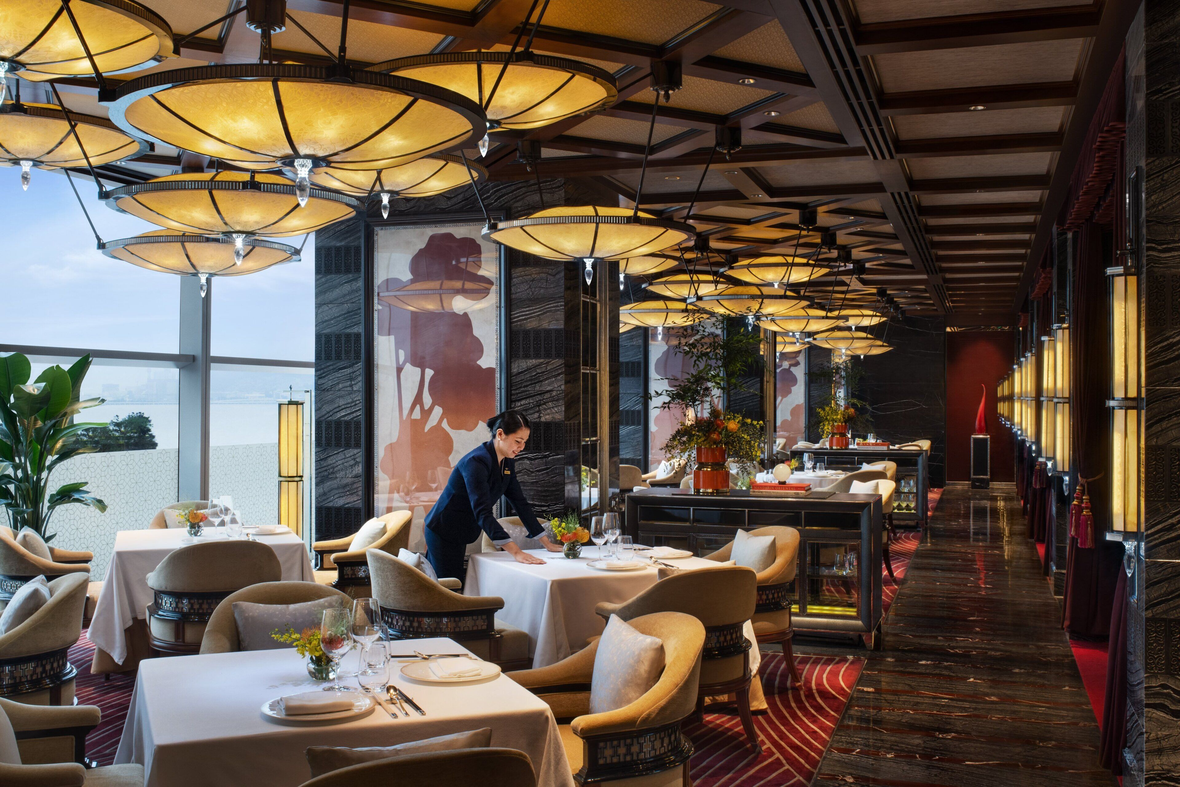 Ein Restaurant mit mehreren Tischen, Stühlen und hängenden Lampen.