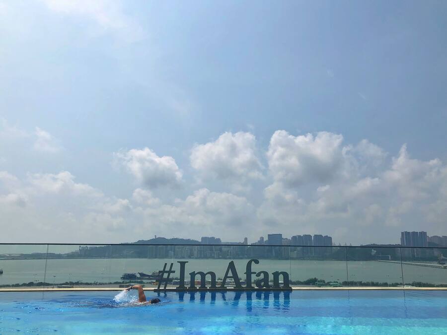 Une piscine offrant une vue sur les gratte-ciel d’une ville et sur une étendue d’eau.