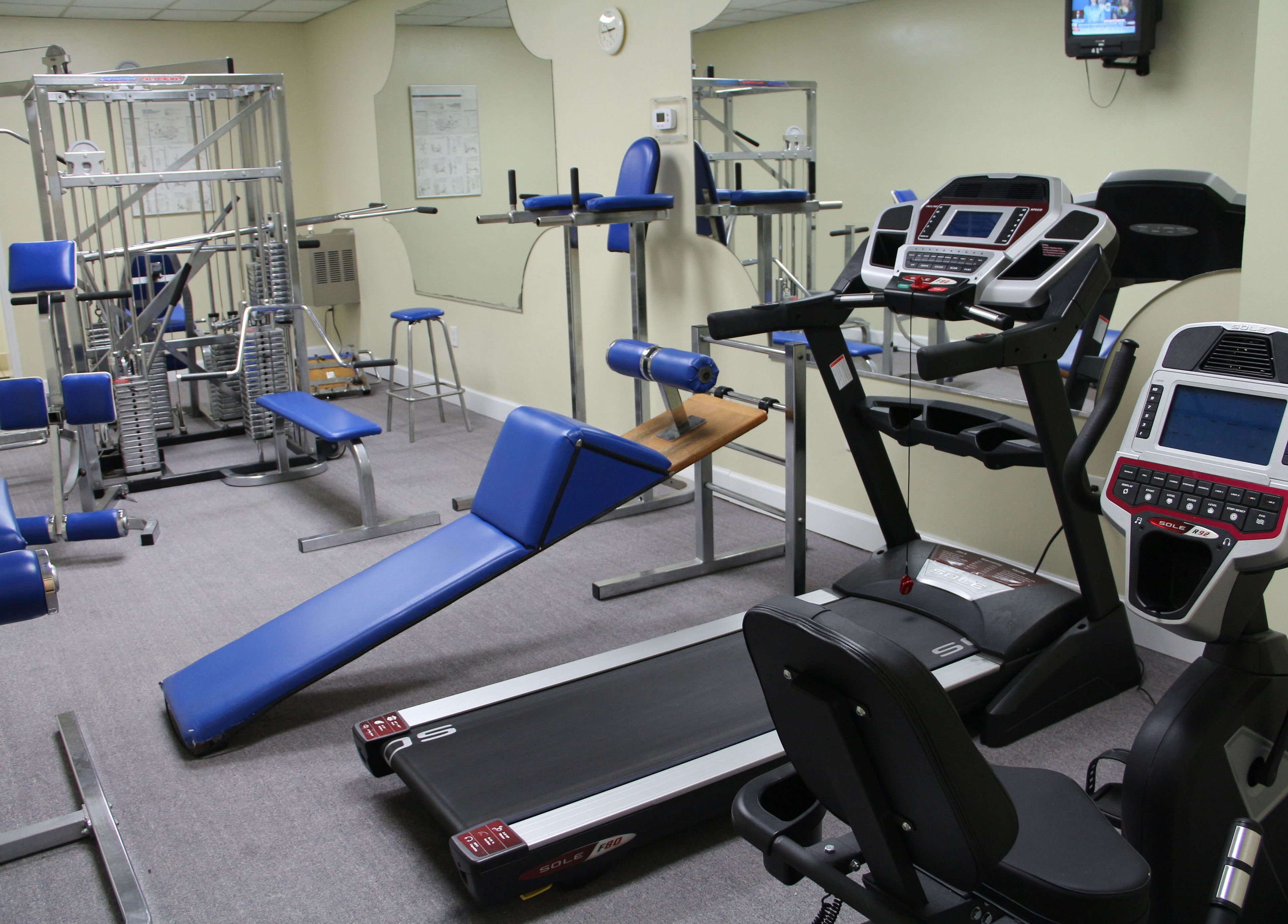 A gym with exercise equipment including treadmills, weight machines, and benches.