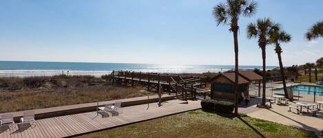 A beachside resort with a wooden deck, a pool, and a view of the ocean.