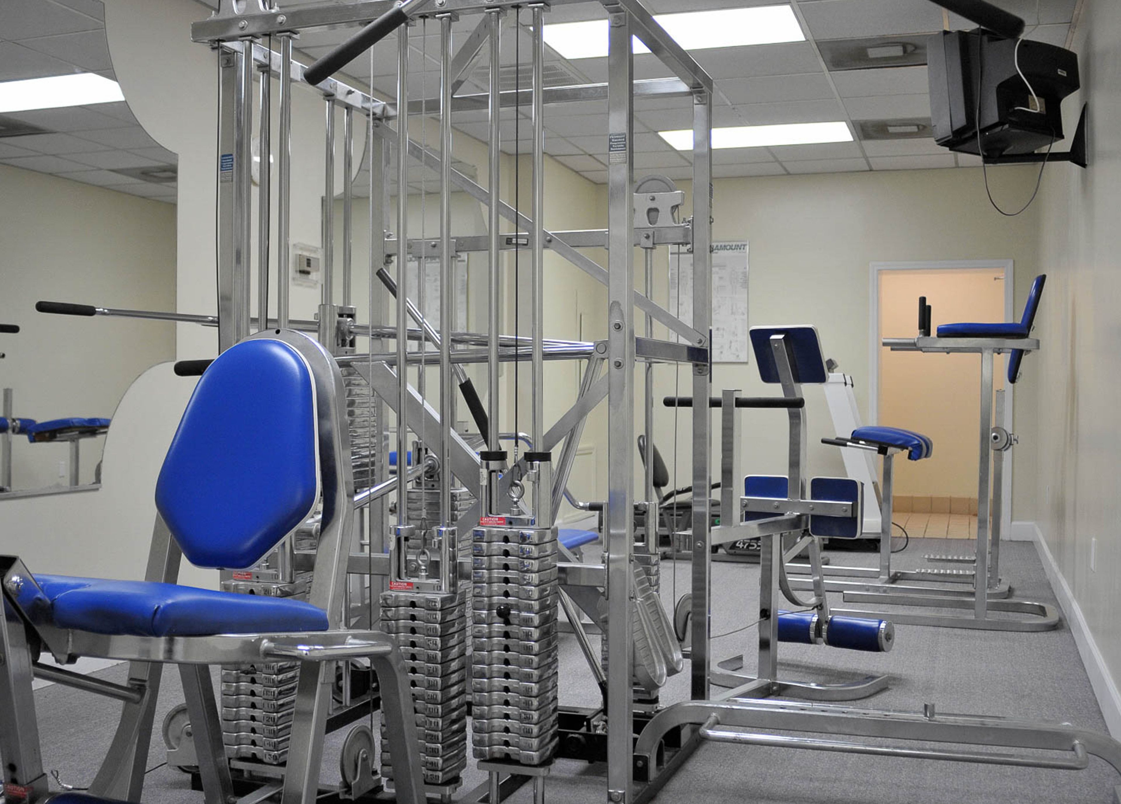 Een sportschool met trainingsapparatuur, waaronder gewichtsblokken en banken.