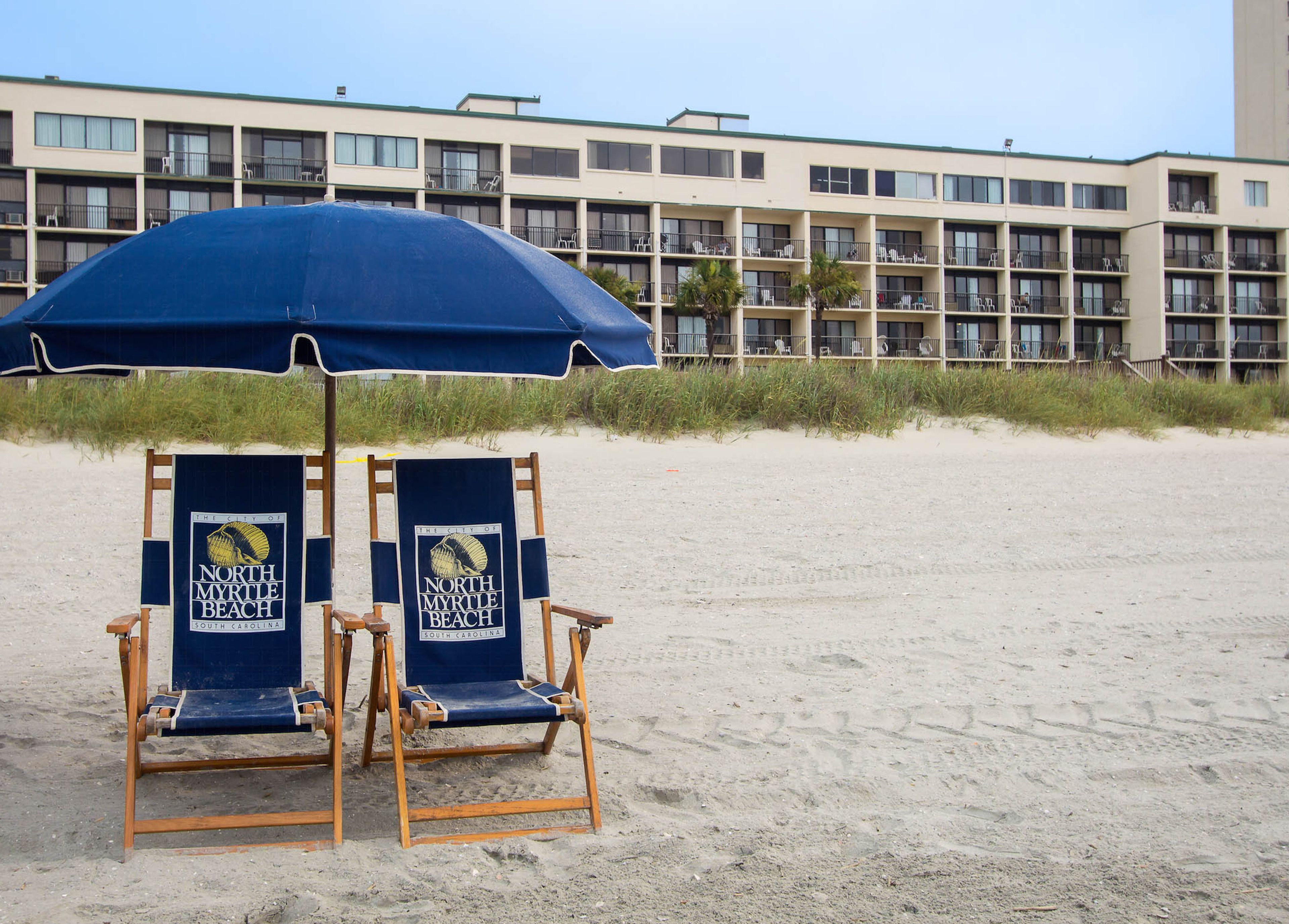 A beach chair and umbrella setup with a sign for North Myrtle Beach.