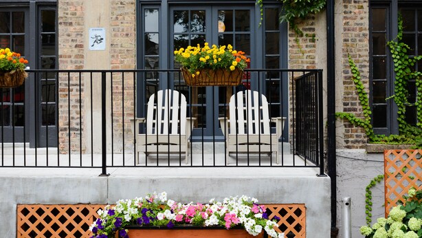 A building with brick walls, large arched windows, and a balcony with two white Adirondack chairs. - Chicago Getaway Hostel (Chicago)