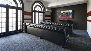 A room with a large window, a ceiling fan, a television, and a black leather sofa. - Chicago Getaway Hostel (Chicago)