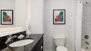 A bathroom with a black sink, white toilet, and a shower with a glass door. There are two framed pictures on the wall.