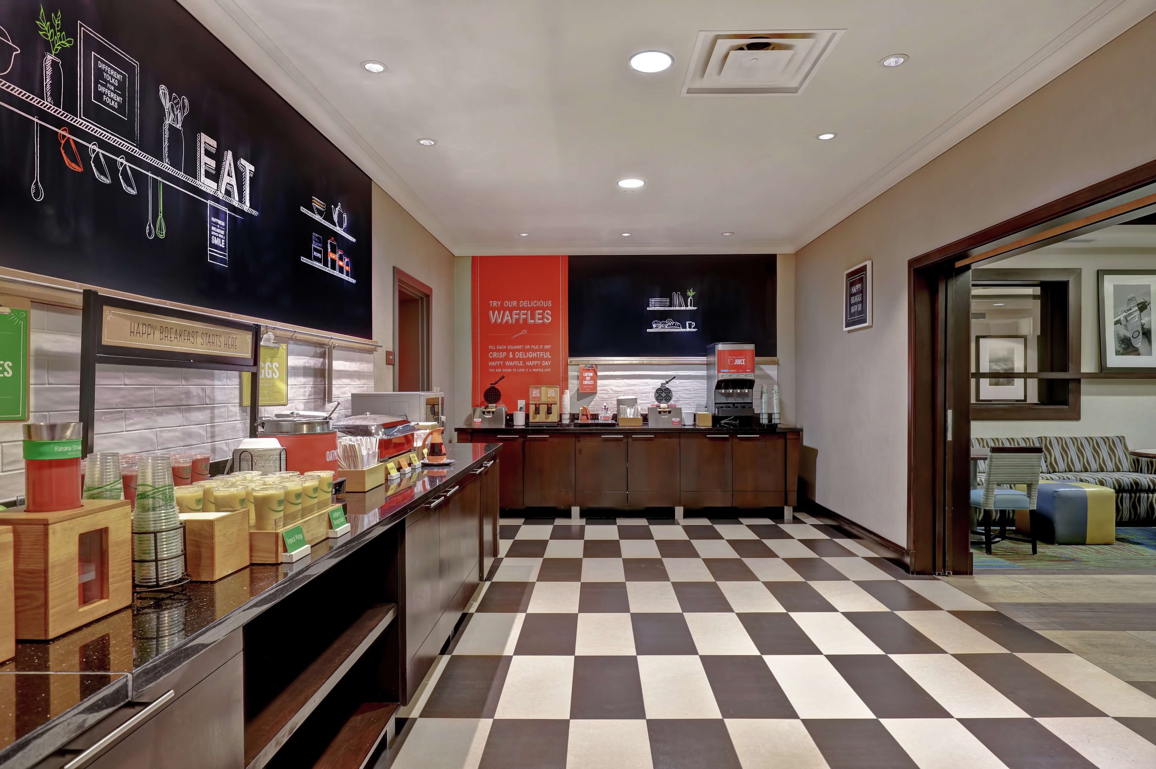 A hotel lobby with a checkered floor, a reception desk, and a wall with a menu board.