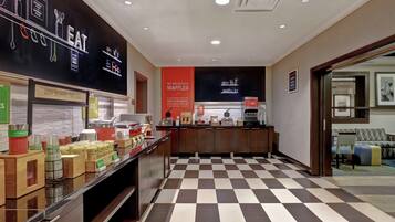 A hotel lobby with a checkered floor, a reception desk, and a wall with a menu board.