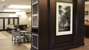 Un vestíbulo de hotel con mostrador de recepción, zona de estar y una fotografía blanco y negro enmarcada en la pared.
