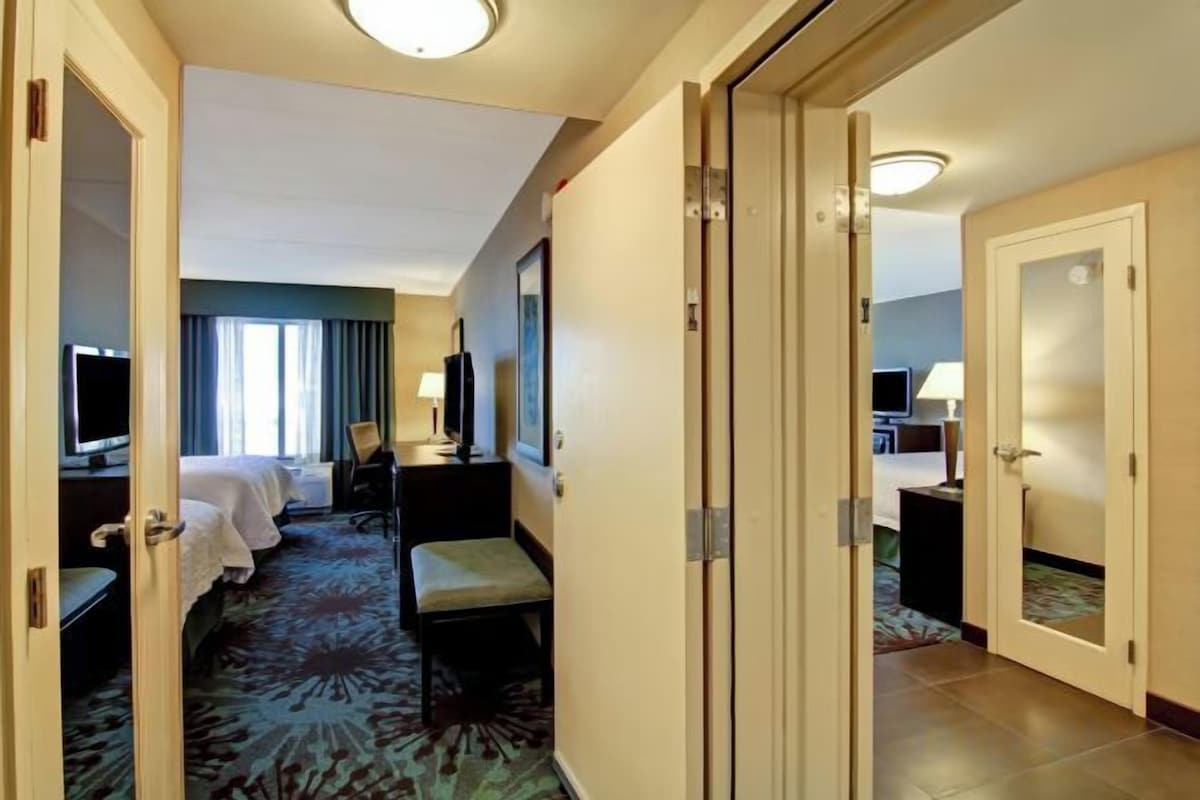 Una camera d'albergo con un letto, una scrivania, una sedia, una televisione e un bagno.