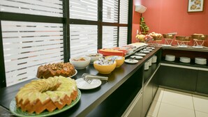 A buffet setup with various food items and a fruit bowl.