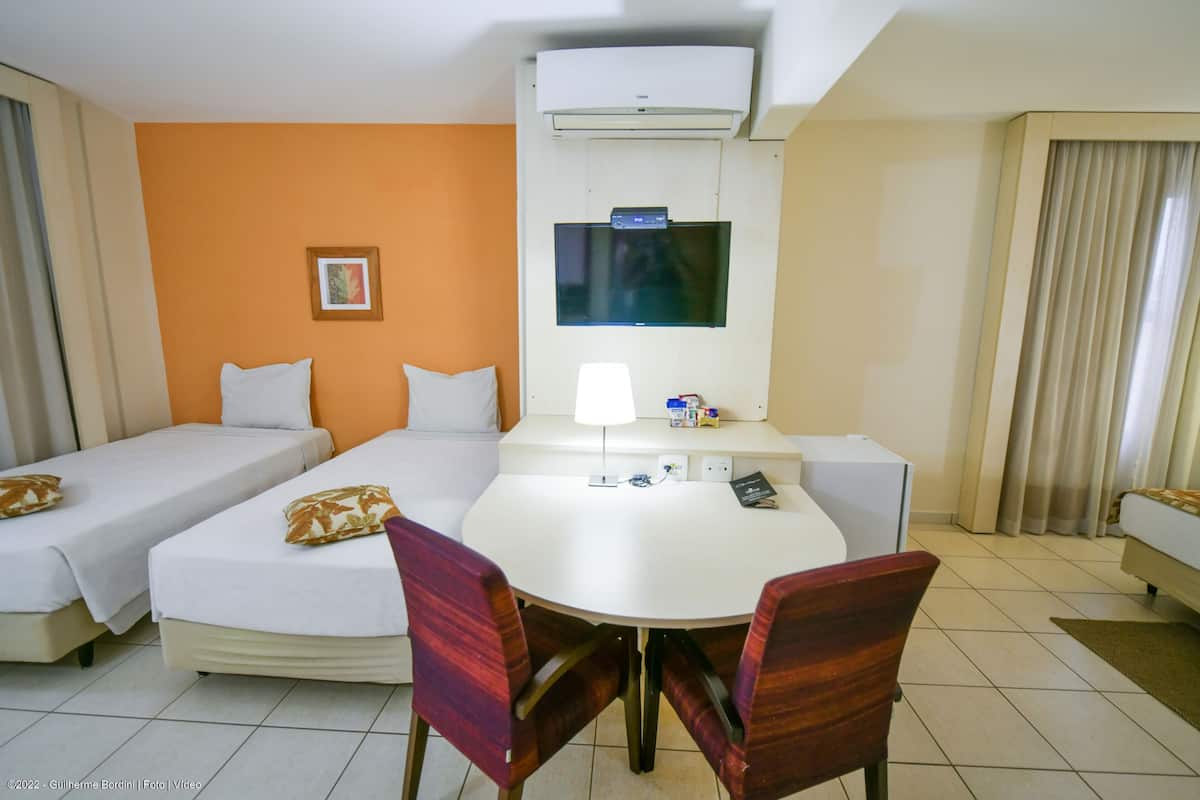 A hotel room with a bed, a desk, a chair, and a TV.