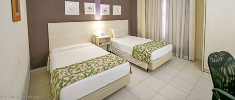 A hotel room with two beds, a nightstand, a desk, and a chair.