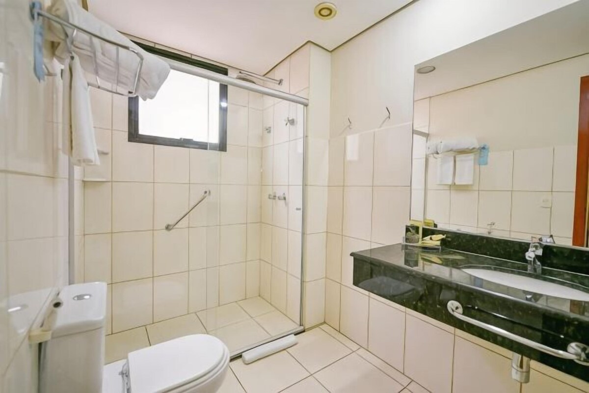 A bathroom with a shower, toilet, sink, and mirror.