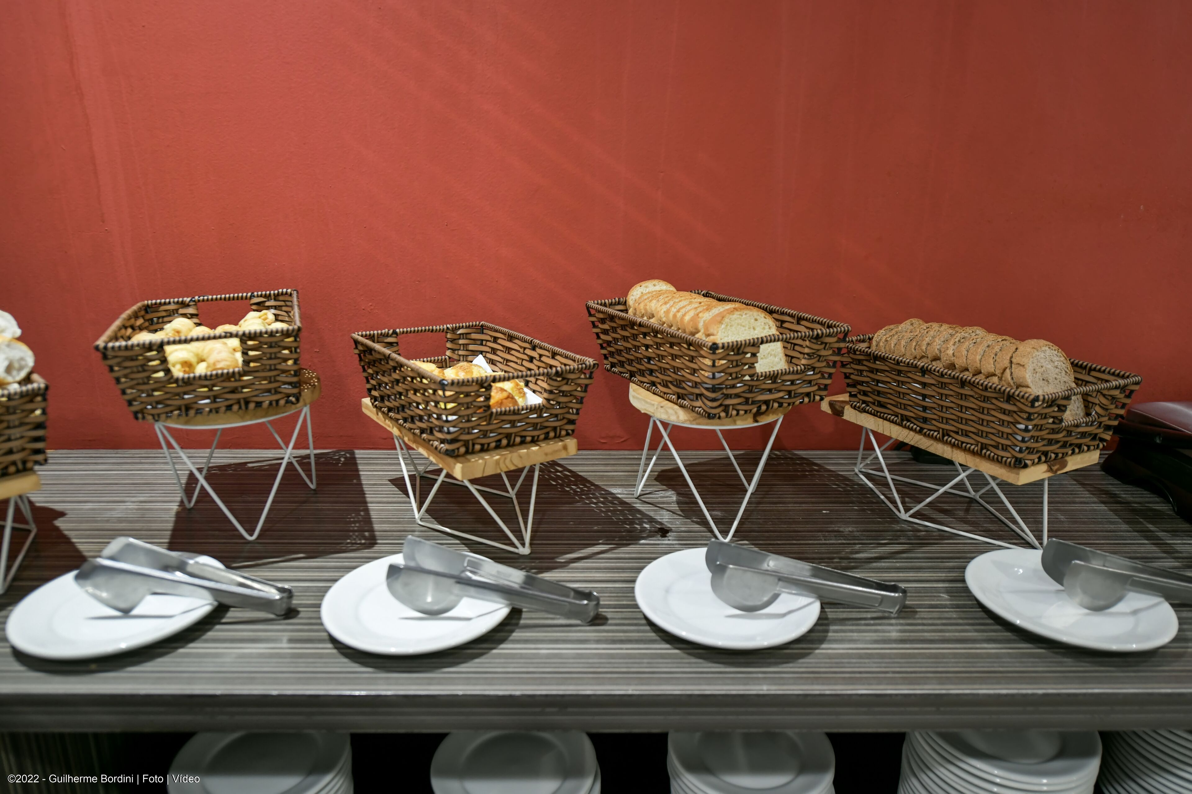 Una mesa con cestas de pan y utensilios.