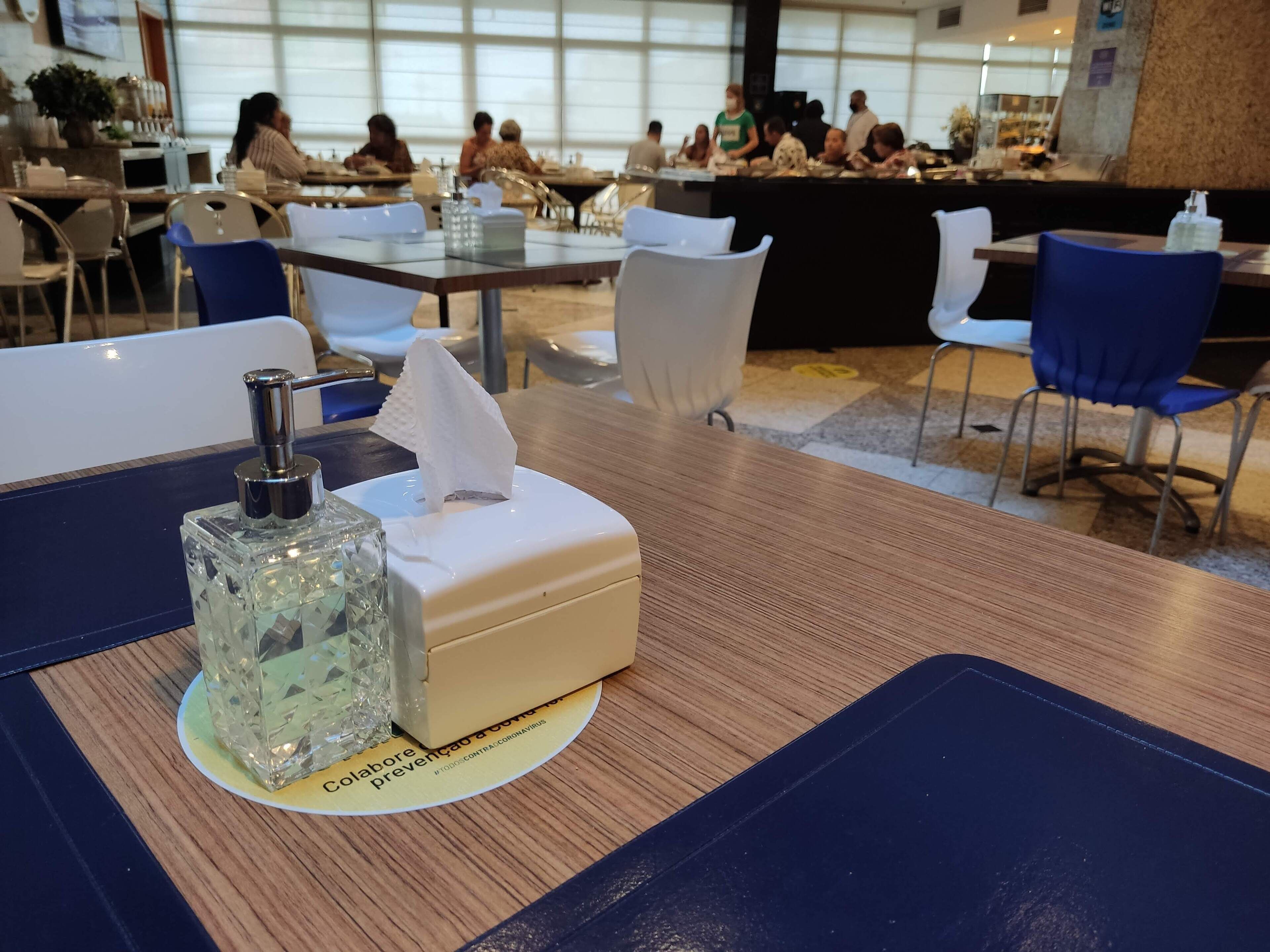 A hotel dining area with tables, chairs, and a tissue box on a table.