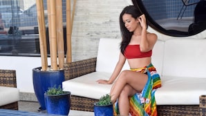 A woman sitting on a white outdoor sofa with a large potted plant beside her. - Reymar Hotel Maceió (Maceió)