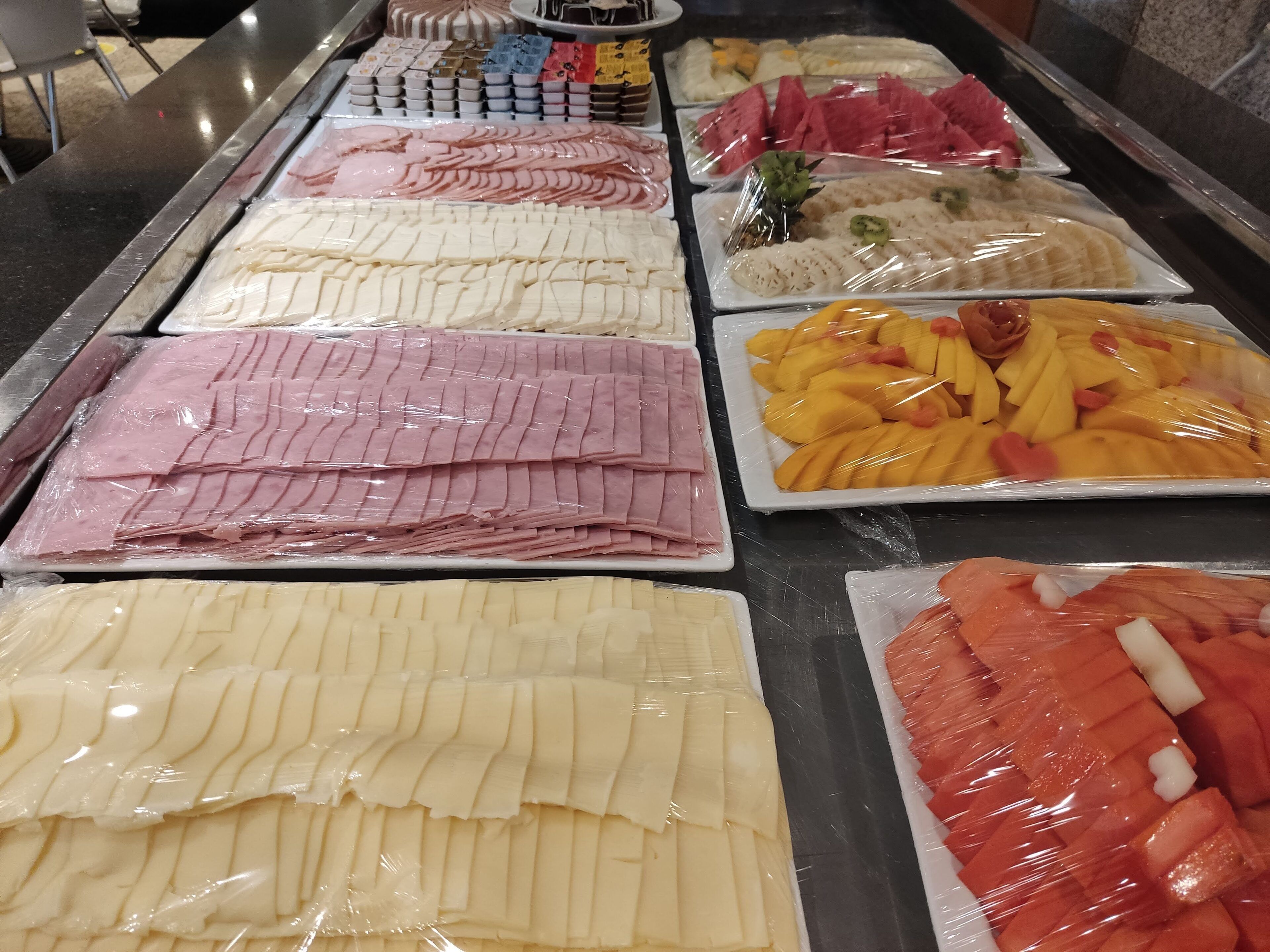 Un bufé con diversas opciones de comida, incluyendo embutidos, quesos y frutas.