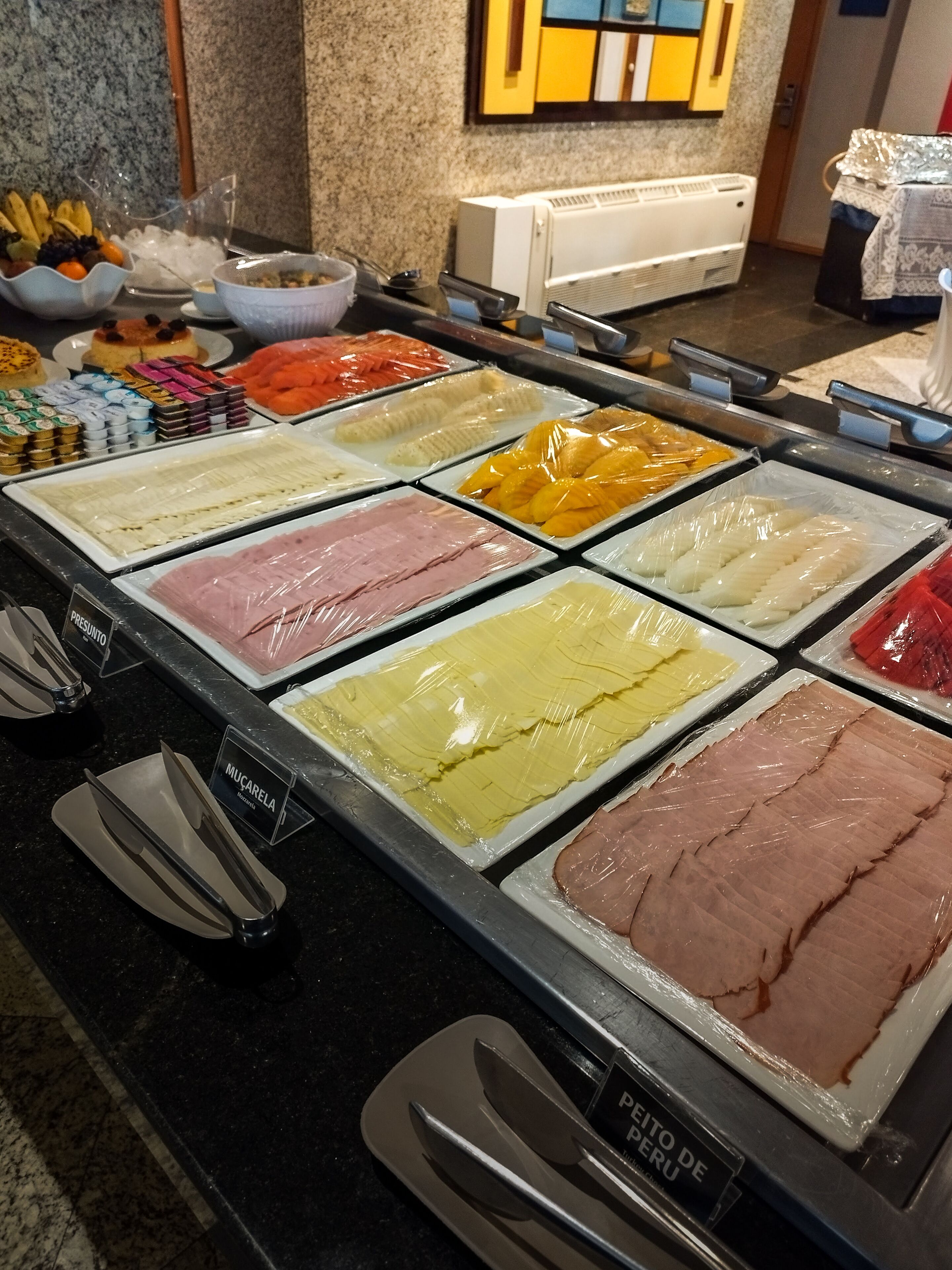 A buffet with various food options including meats, fruits, and desserts.