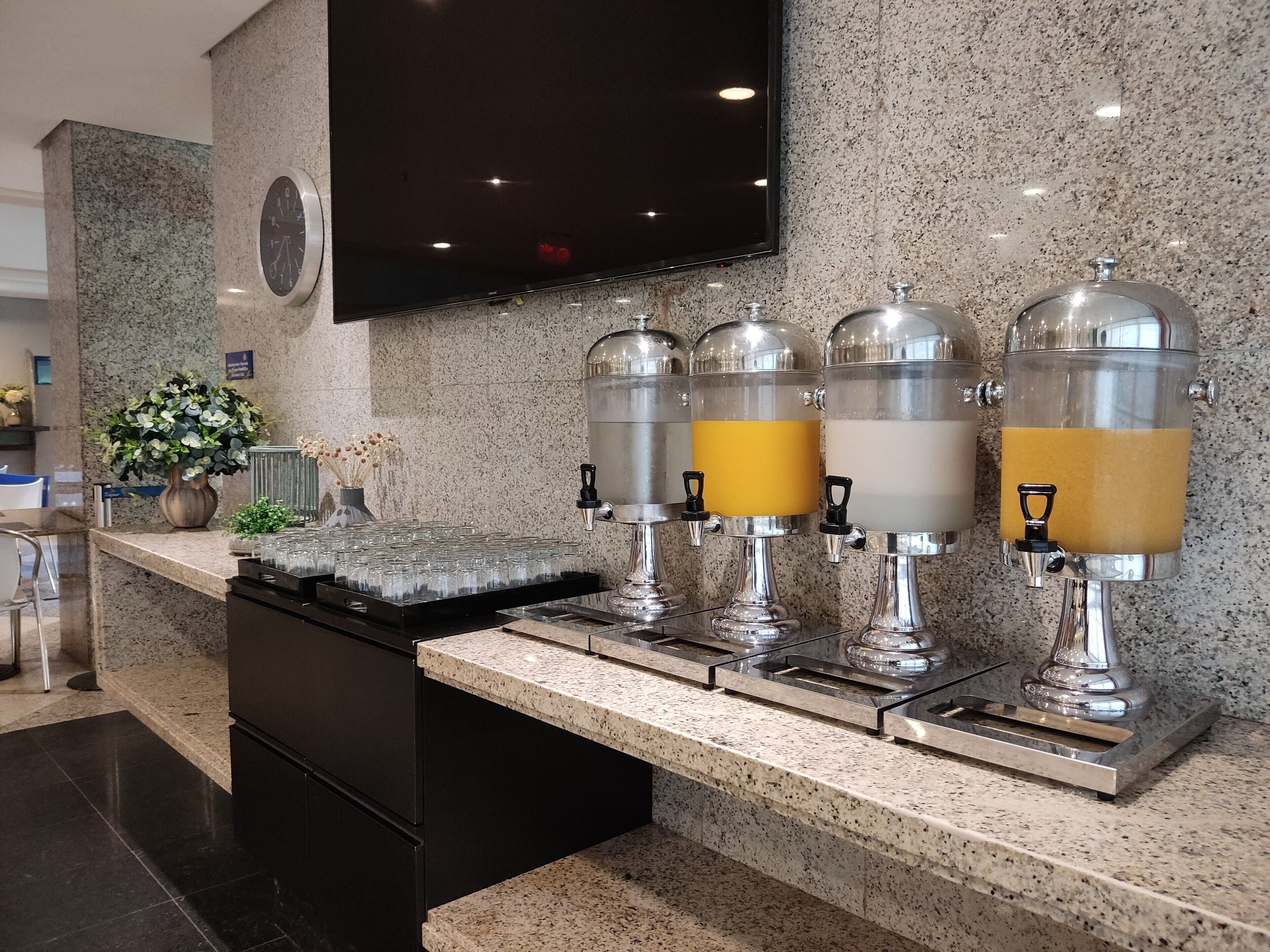 A modern kitchen area with granite countertops, a built-in stove, and a coffee station with four dispensers.
