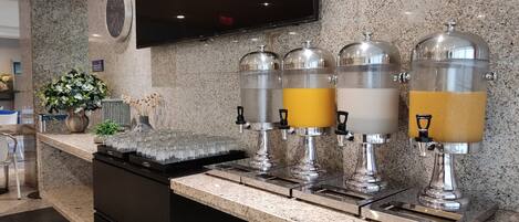 A modern kitchen area with granite countertops, a built-in stove, and a coffee station with four dispensers.