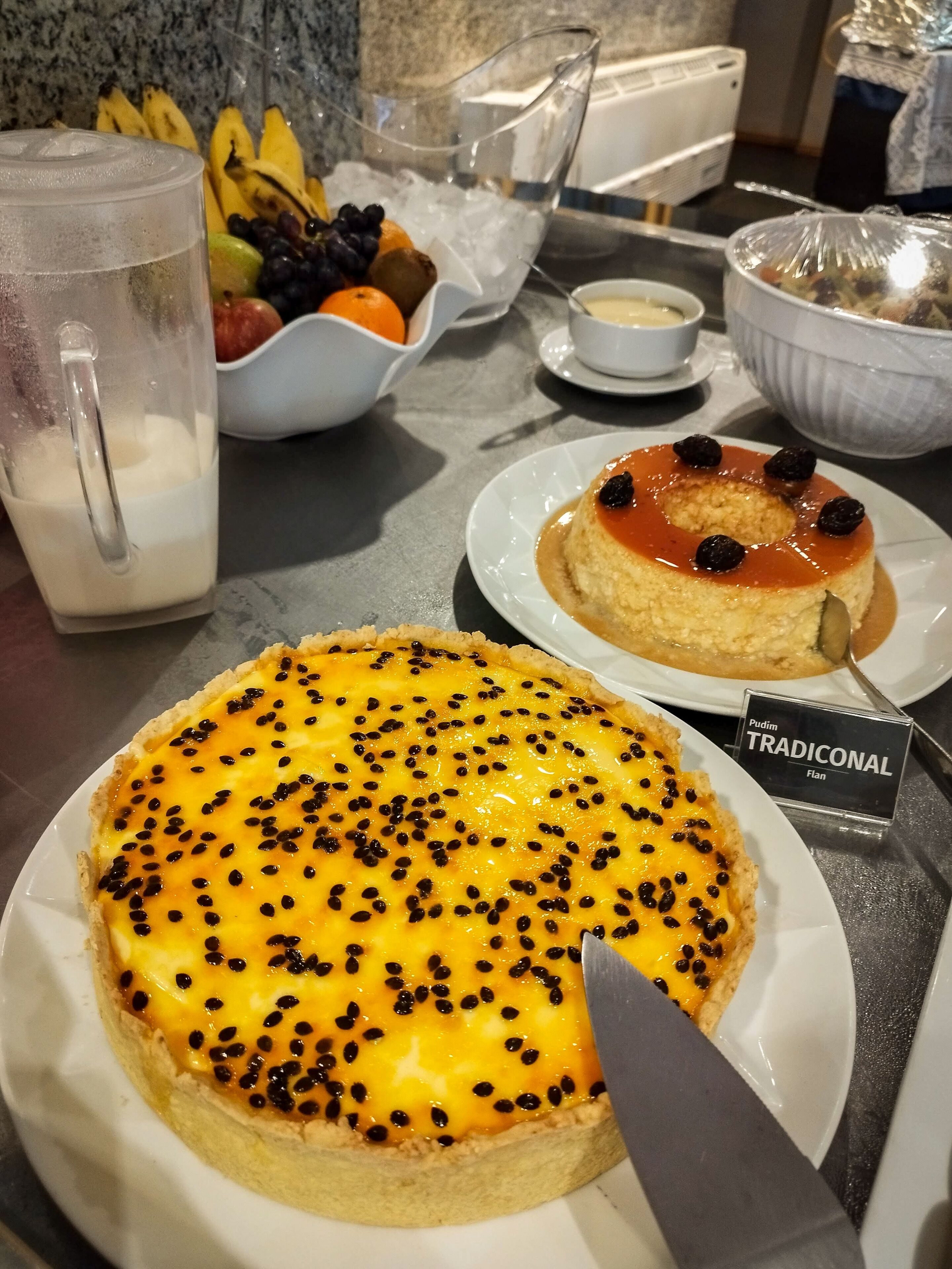 A dessert table with a variety of dishes, including a custard tart with black sesame seeds and a panna cotta with berries.