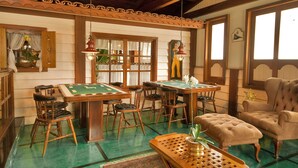 A room with a pool table, four chairs, a tufted armchair, and a wooden coffee table.