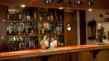 A bar area with shelves of various liquor bottles, a counter with drinks, and a statue.