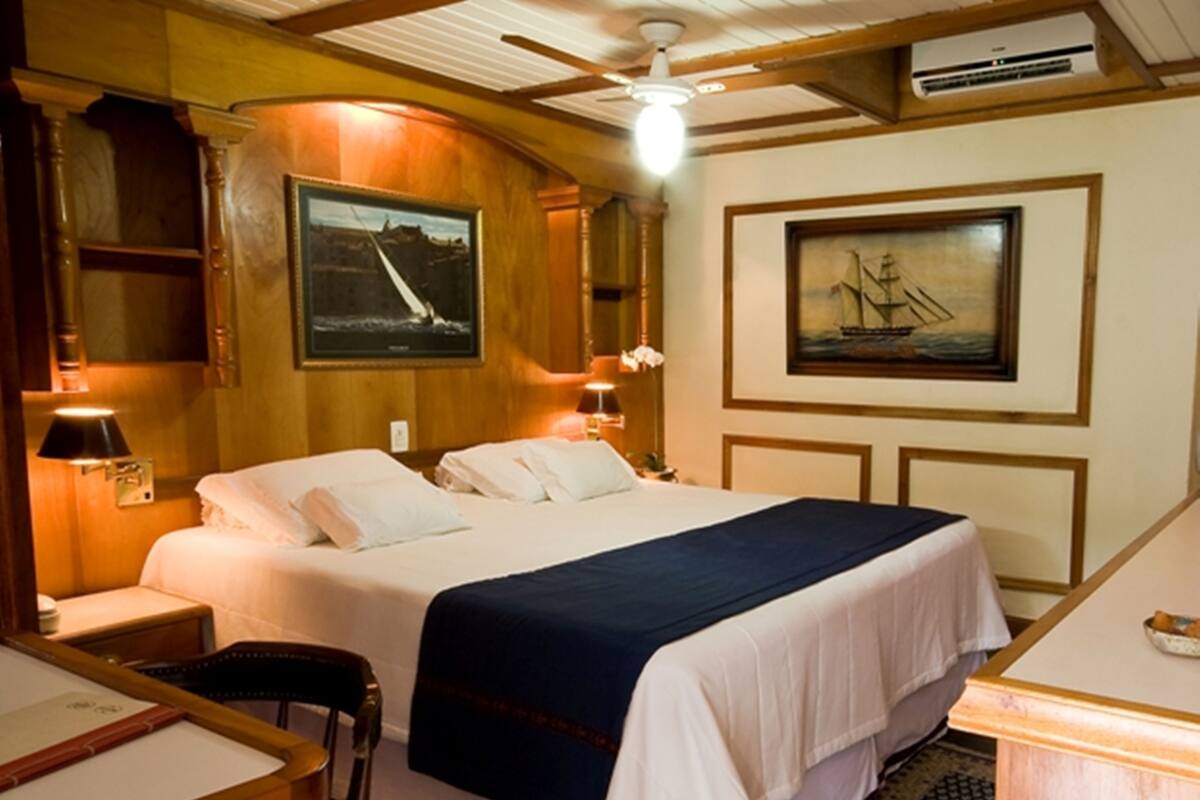 Habitación de hotel con una cama, un escritorio, una silla y dos cuadros en las paredes.