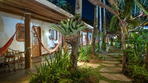 A tropical resort with a hammock, wooden chairs, and a stone pathway.
