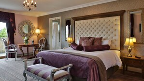 A spacious bedroom with a large bed, a chandelier, a mirror, and a view of the outdoors.