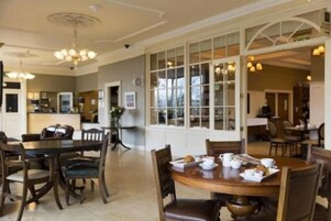 A dining area with a large window, wooden tables, and chairs.