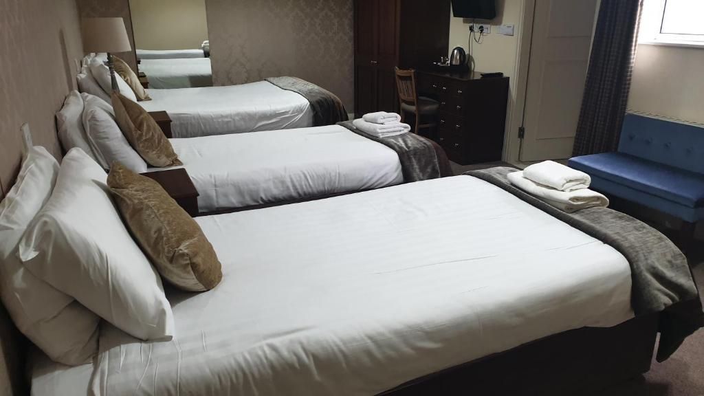 A hotel room with two beds, a desk, a chair, and a small seating area.