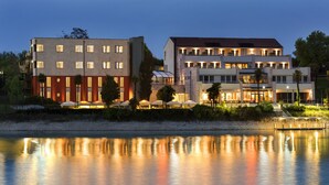 Un hôtel composé de plusieurs bâtiments, avec un plan d’eau aux reflets changeants à l’avant et des espaces de détente en plein air.