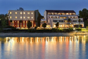 Un hotel con varias construcciones, una masa de agua reflectante al frente y zonas de estar al aire libre.