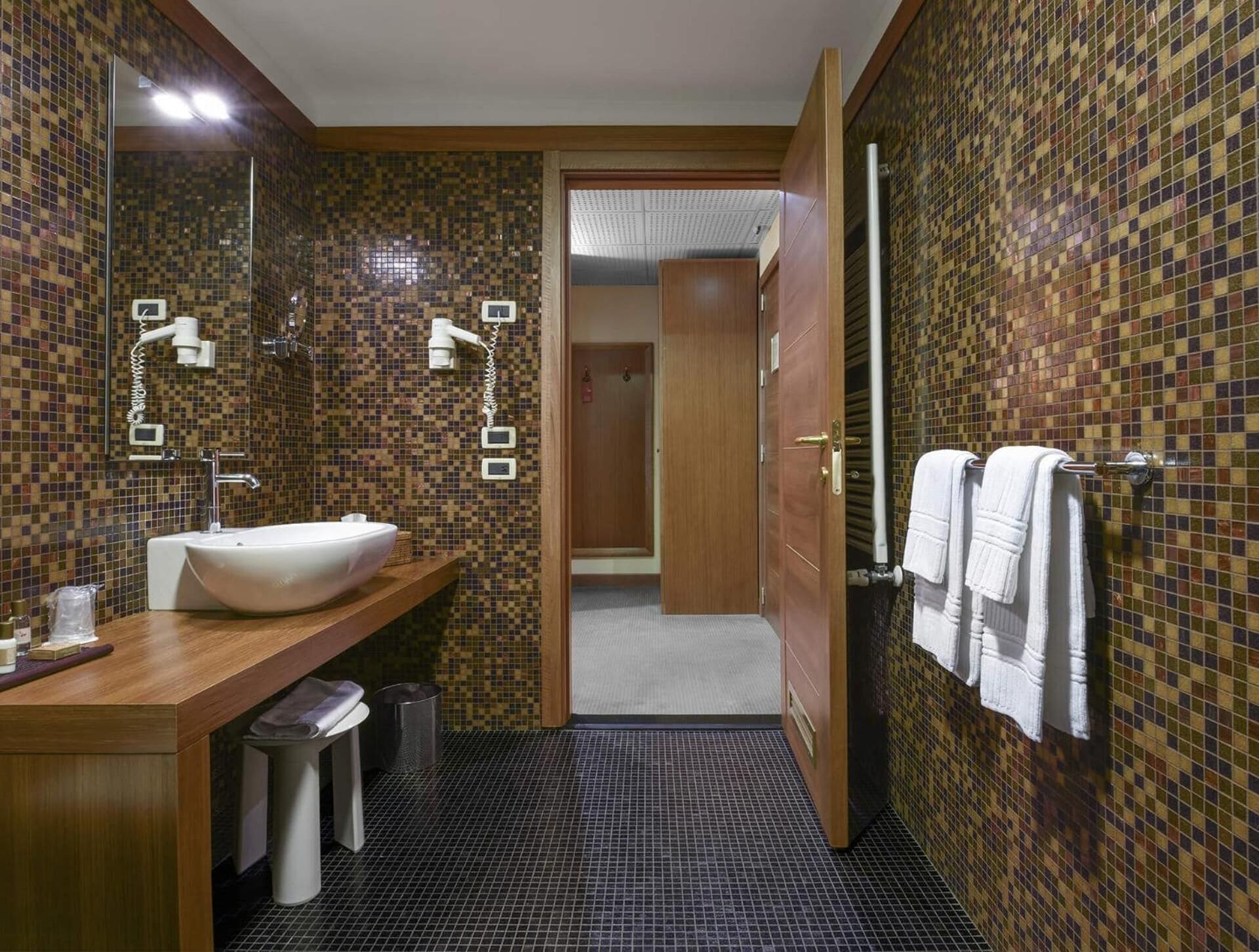 Ein modernes Badezimmer mit einem großen Waschbecken, einem Spiegel und einem Handtuchhalter.
