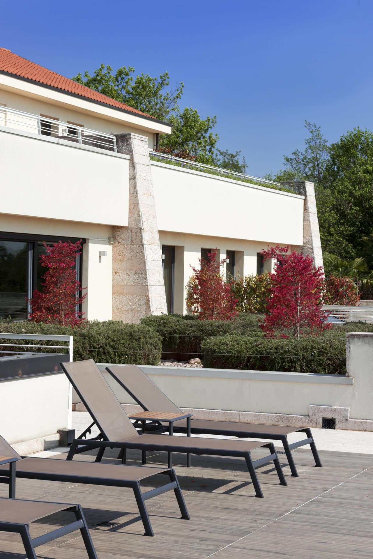 A modern building with a rooftop deck featuring lounge chairs and a small table.