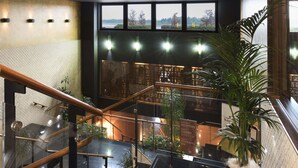 Un intérieur moderne avec un escalier, de grandes fenêtres et des plantes d’intérieur.