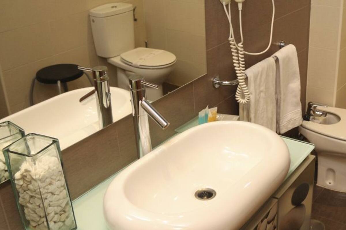 Une salle de bain moderne avec un grand lavabo, deux toilettes, un bidet et une poubelle.