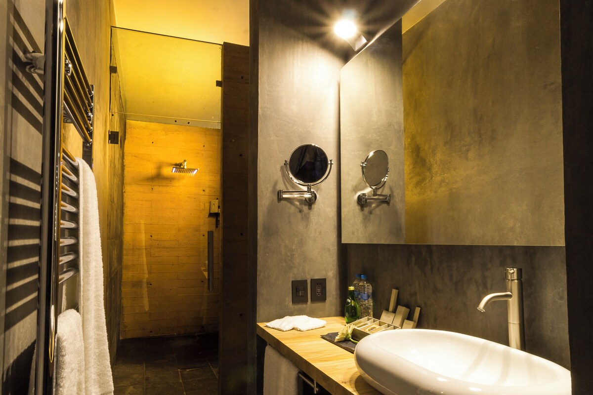 Une salle de bain moderne avec un grand miroir, un lavabo et un porte-serviettes.