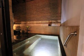 Une salle de bain dotée d’une douche à parois de verre, de lambris en bois et d’une barre d’appui.