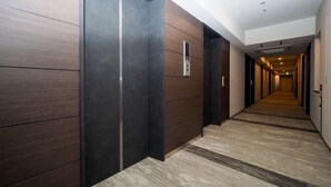A modern hotel corridor with wooden panel walls, a carpeted floor, and a long hallway leading to a door at the end. - Best Western Hotel Fino Osaka Shinsaibashi (Osaka)