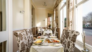 Un comedor con una mesa preparada para el desayuno, que incluye platos de comida, una taza de café y un candelabro.