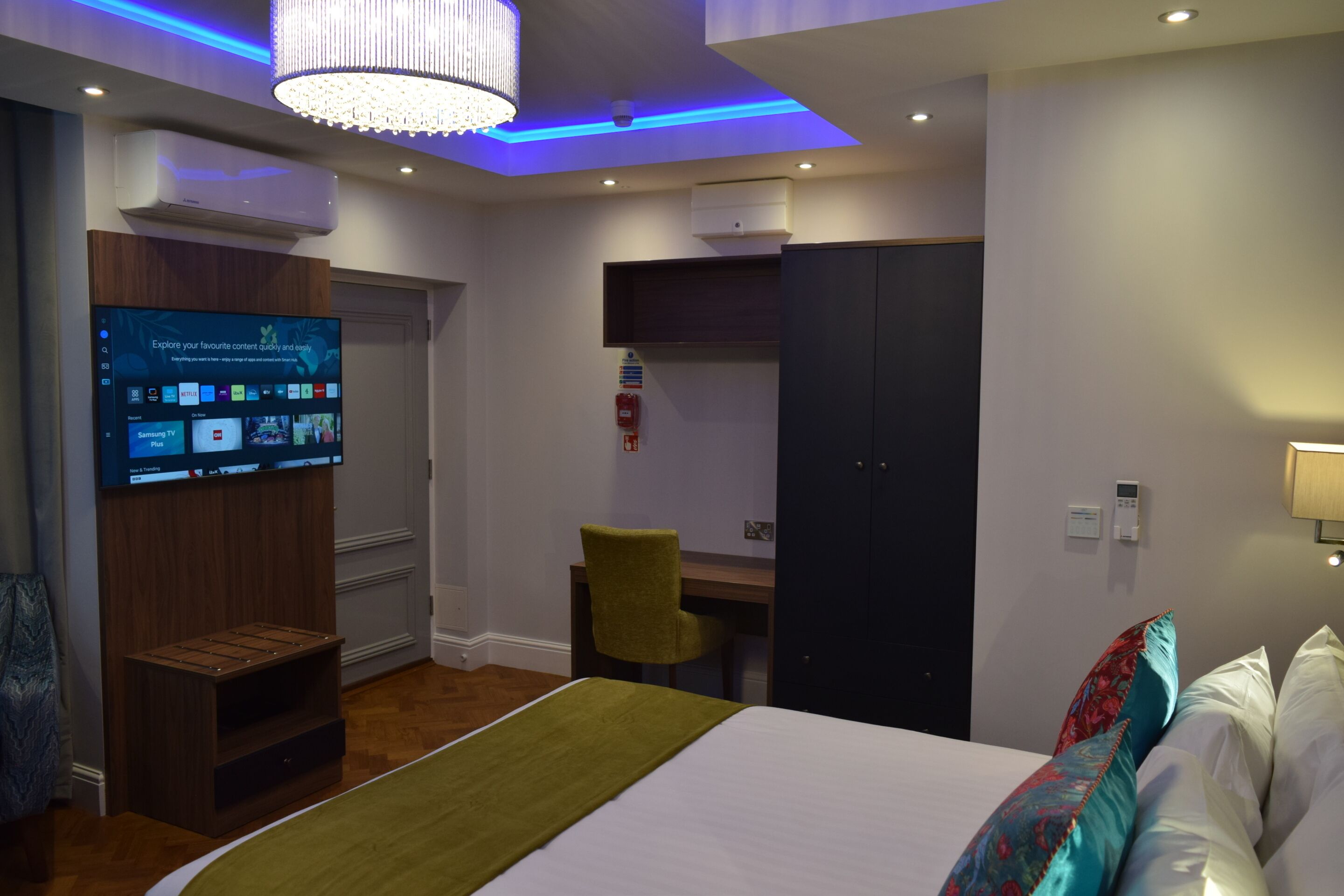 A hotel room with a bed, a desk, a television, and a wardrobe.