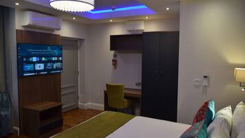 A hotel room with a bed, a desk, a television, and a wardrobe.