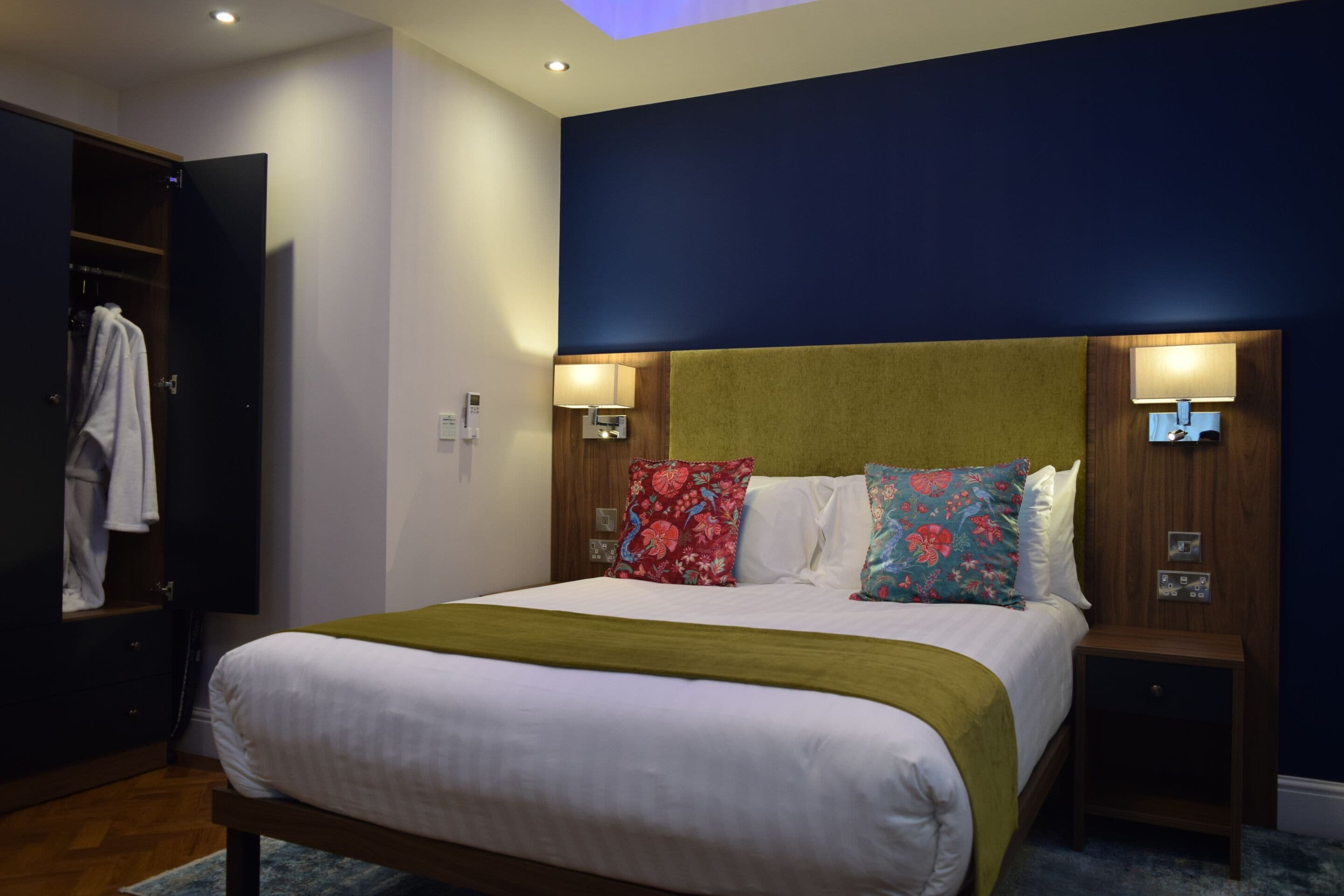 A hotel room with a bed, bedside tables, a wardrobe, and a nightstand.