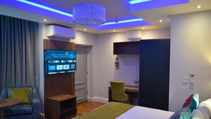 Una habitación de hotel moderna con una cama grande, un televisor montado en la pared, un escritorio y una silla.
