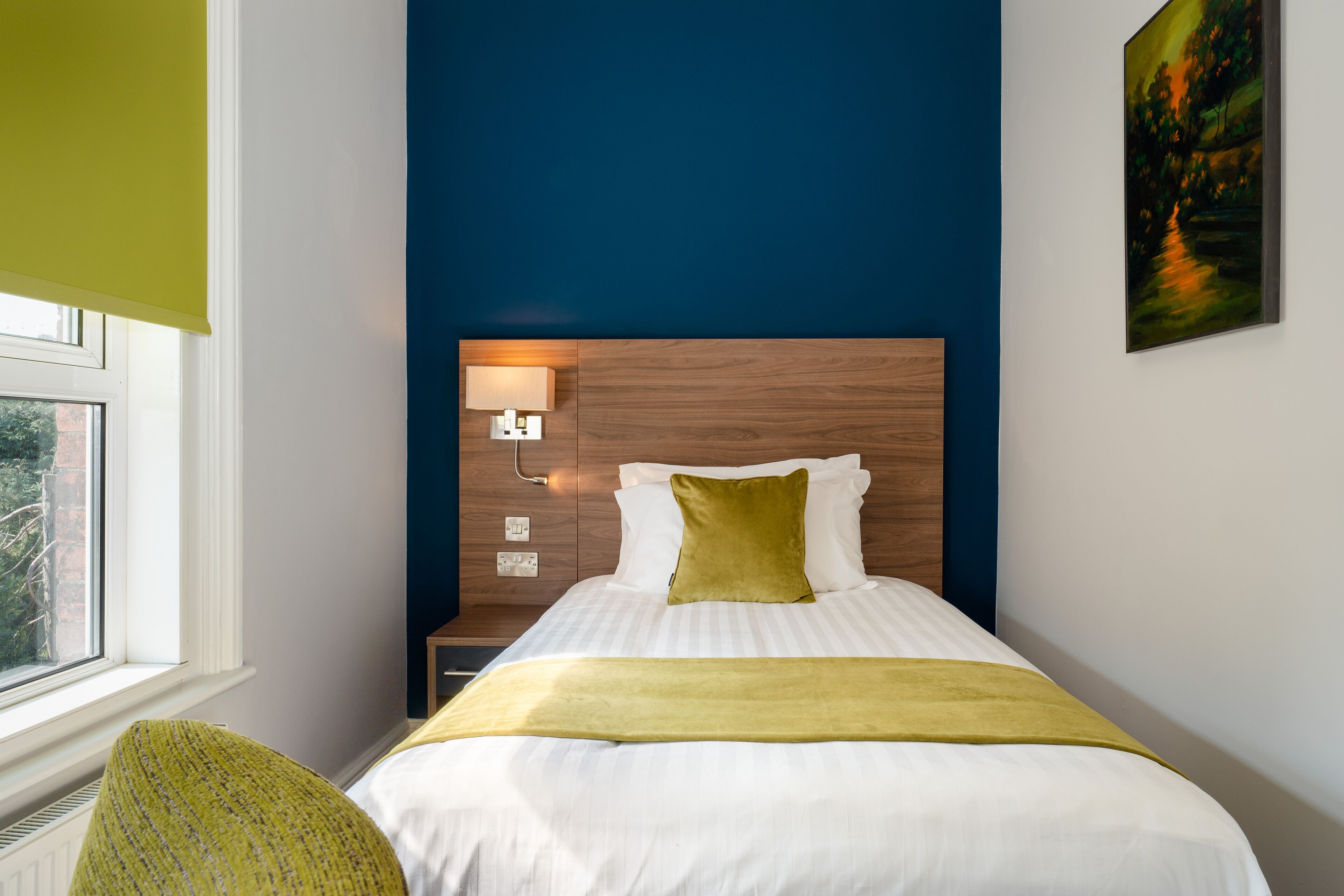 A neatly arranged hotel room with a bed, bedside lamp, and a window.