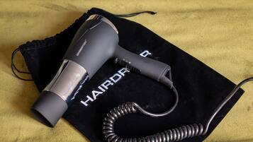 Ein Haartrockner mit einem aufgewickelten Kabel auf einer schwarzen Samina mit dem Schriftzug "HAIRDRY".